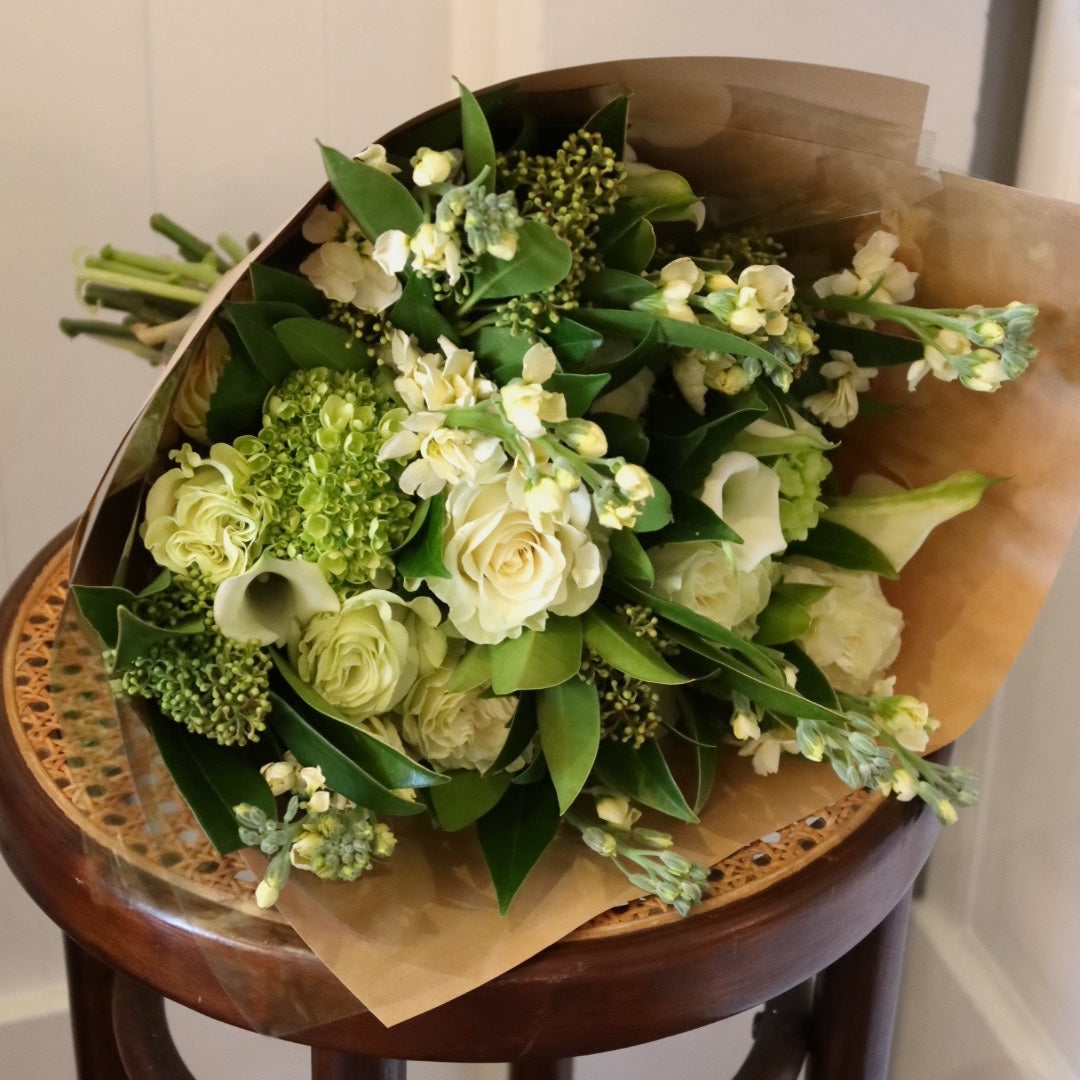 Bouquet of green and white flowers on a wooden stool